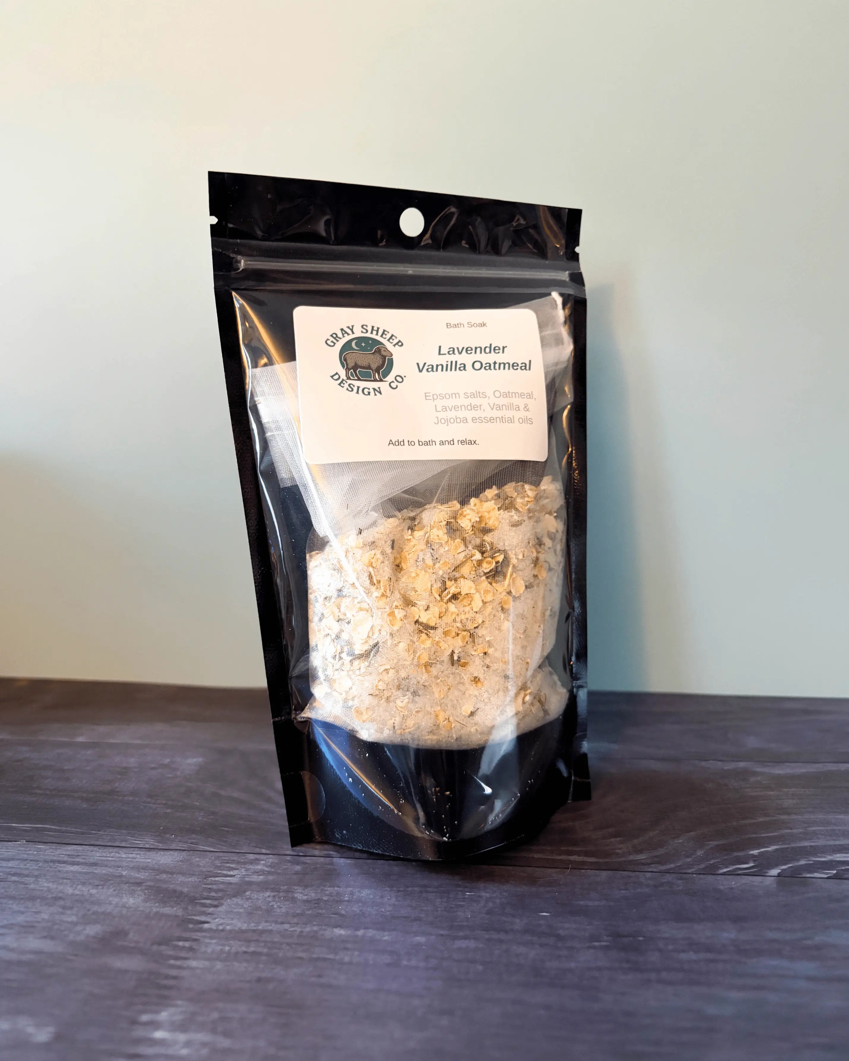 Lavender Vanilla Oatmeal bath soak in a resealable black pouch, oat-flecked salts visible through the window.