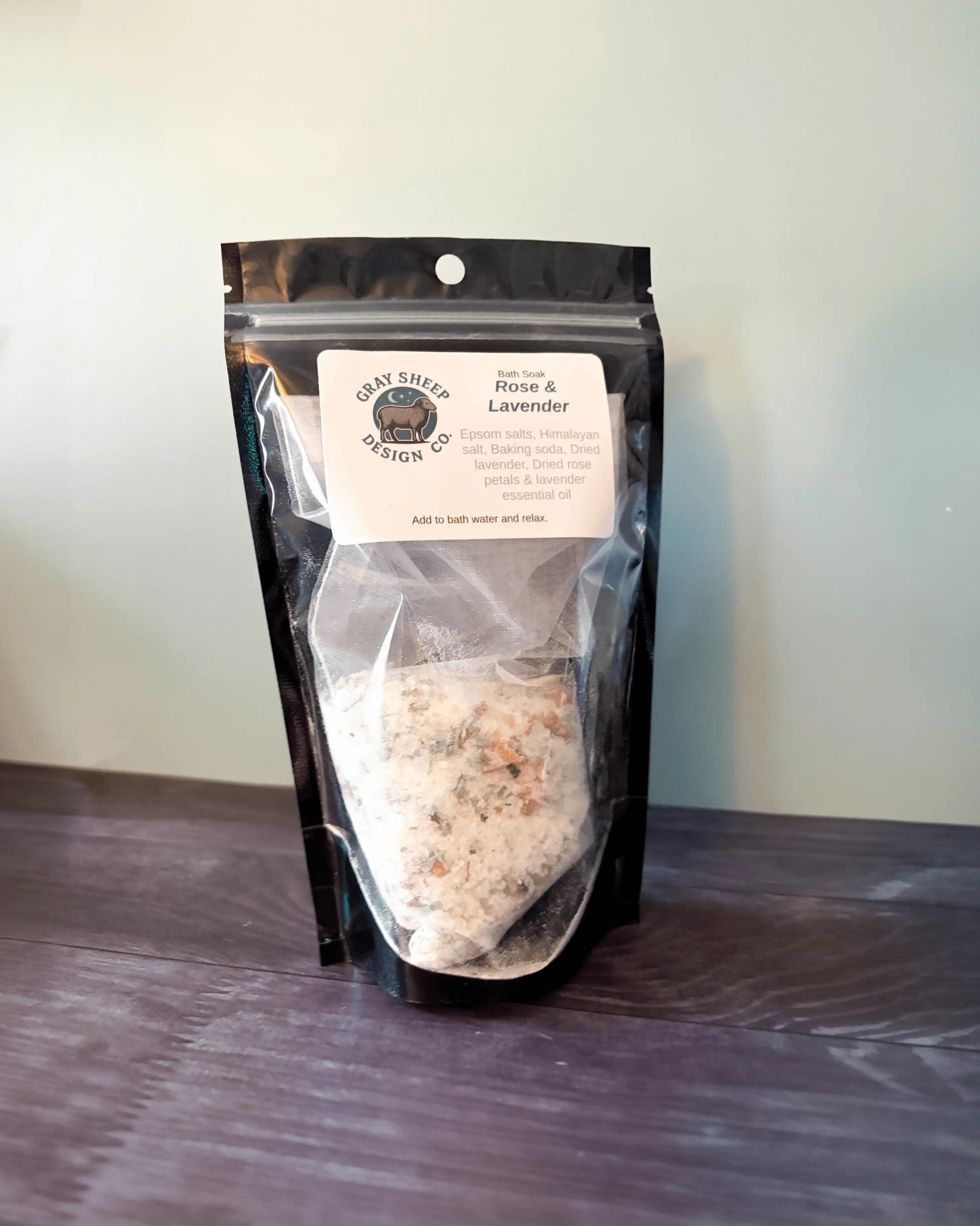 Rose & Lavender bath soak in a resealable black pouch, pink-flecked salts visible through the window.