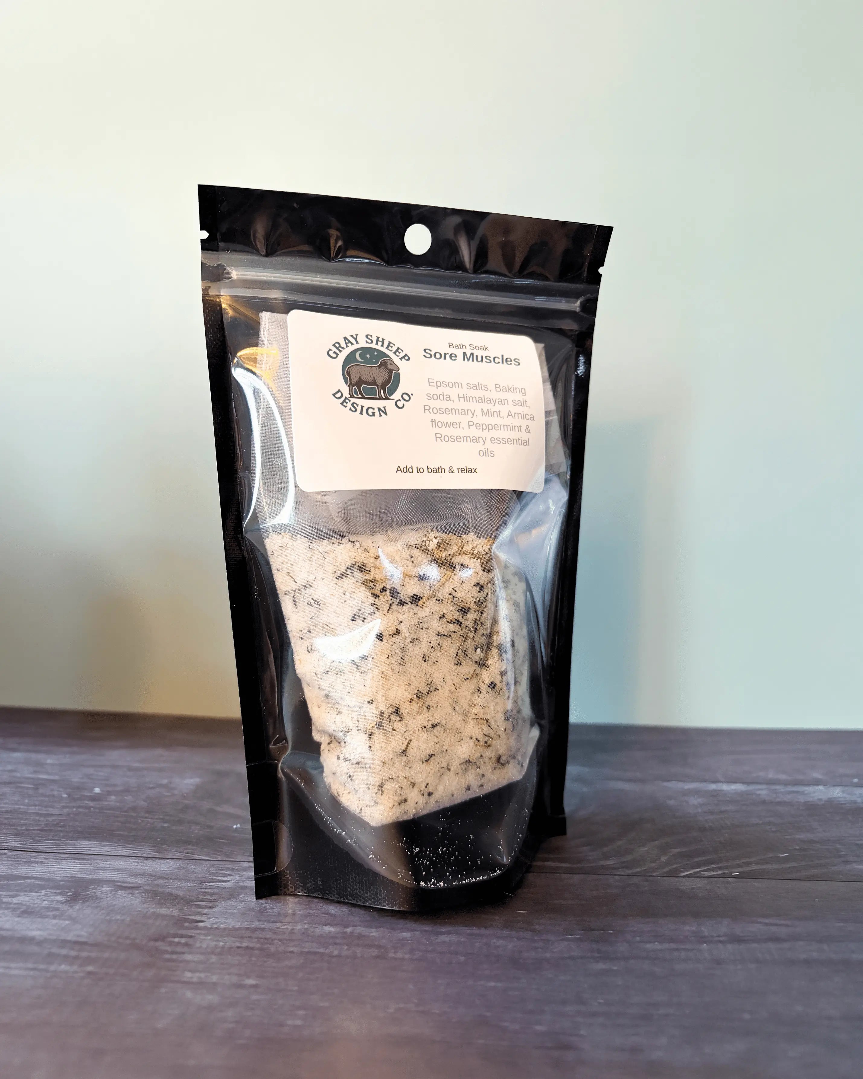 Sore Muscles bath soak in a resealable black pouch, speckled herbal salts visible through the window.