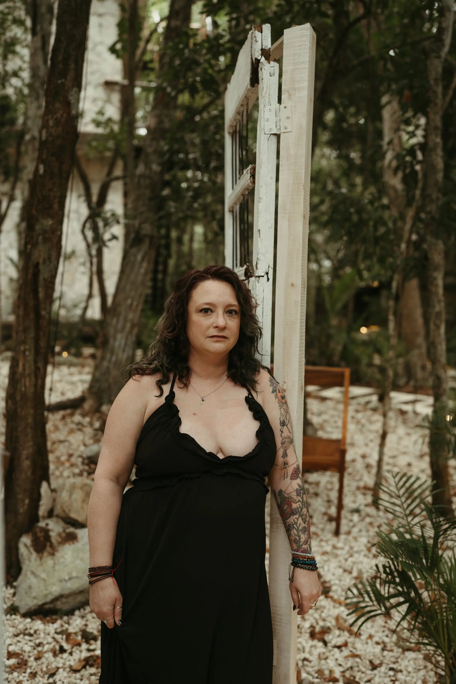 Ashley, founder of Gray Sheep Design Co., standing outdoors in a black dress beside a weathered door frame.