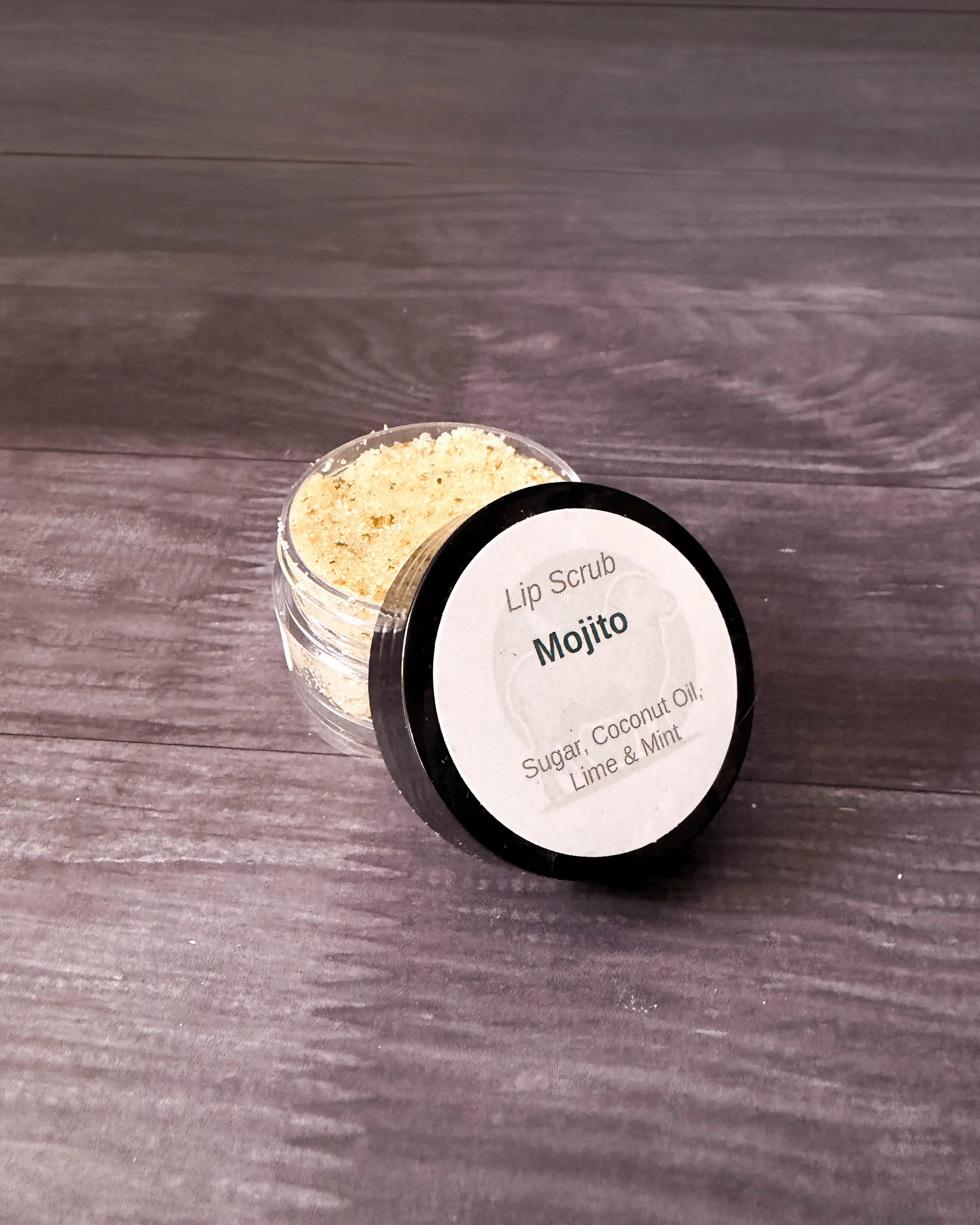 Mojito lip scrub in a small clear jar with a black labeled lid.