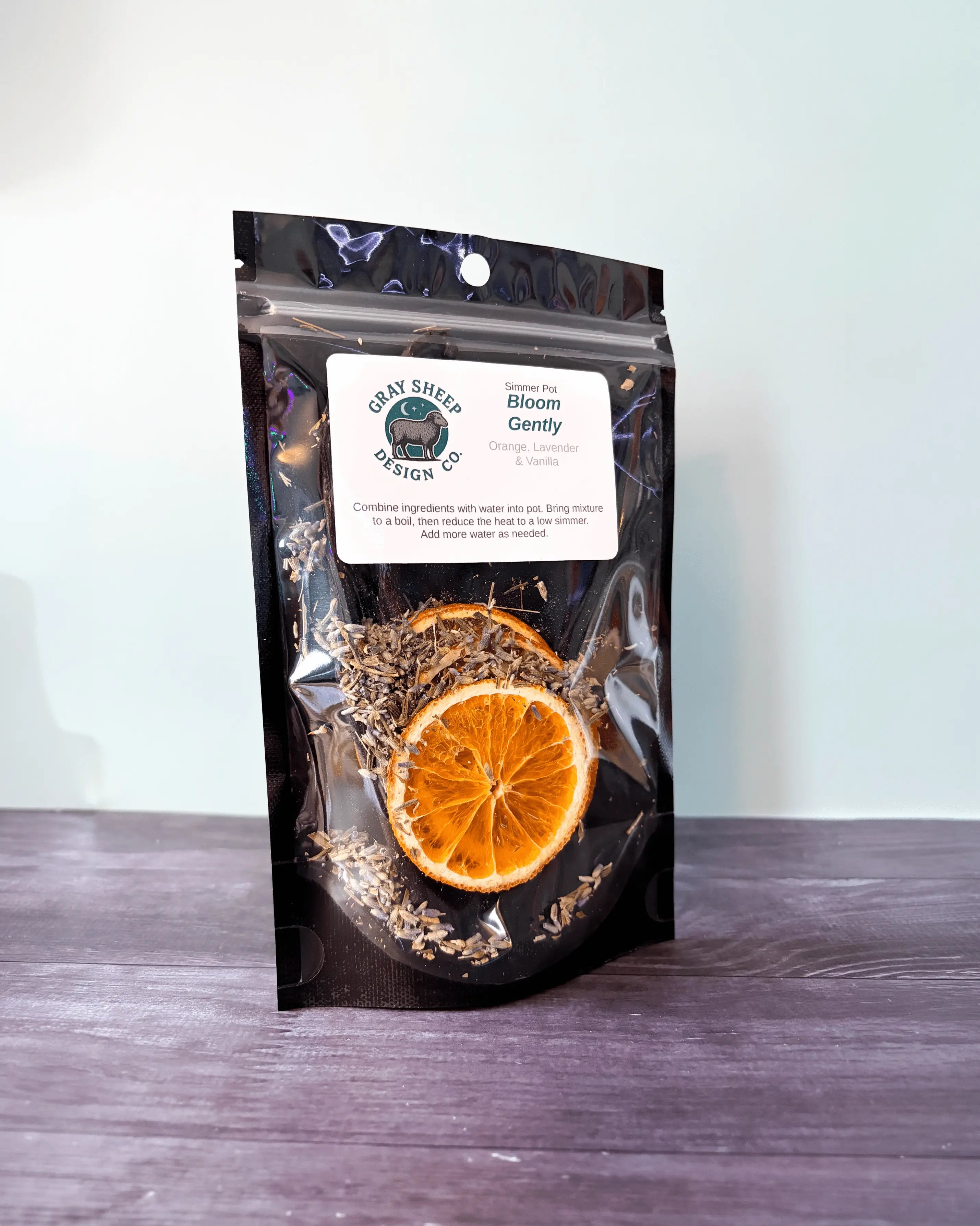 Bloom Gently simmer pot in a resealable black pouch, a dried orange slice and lavender visible through the window.