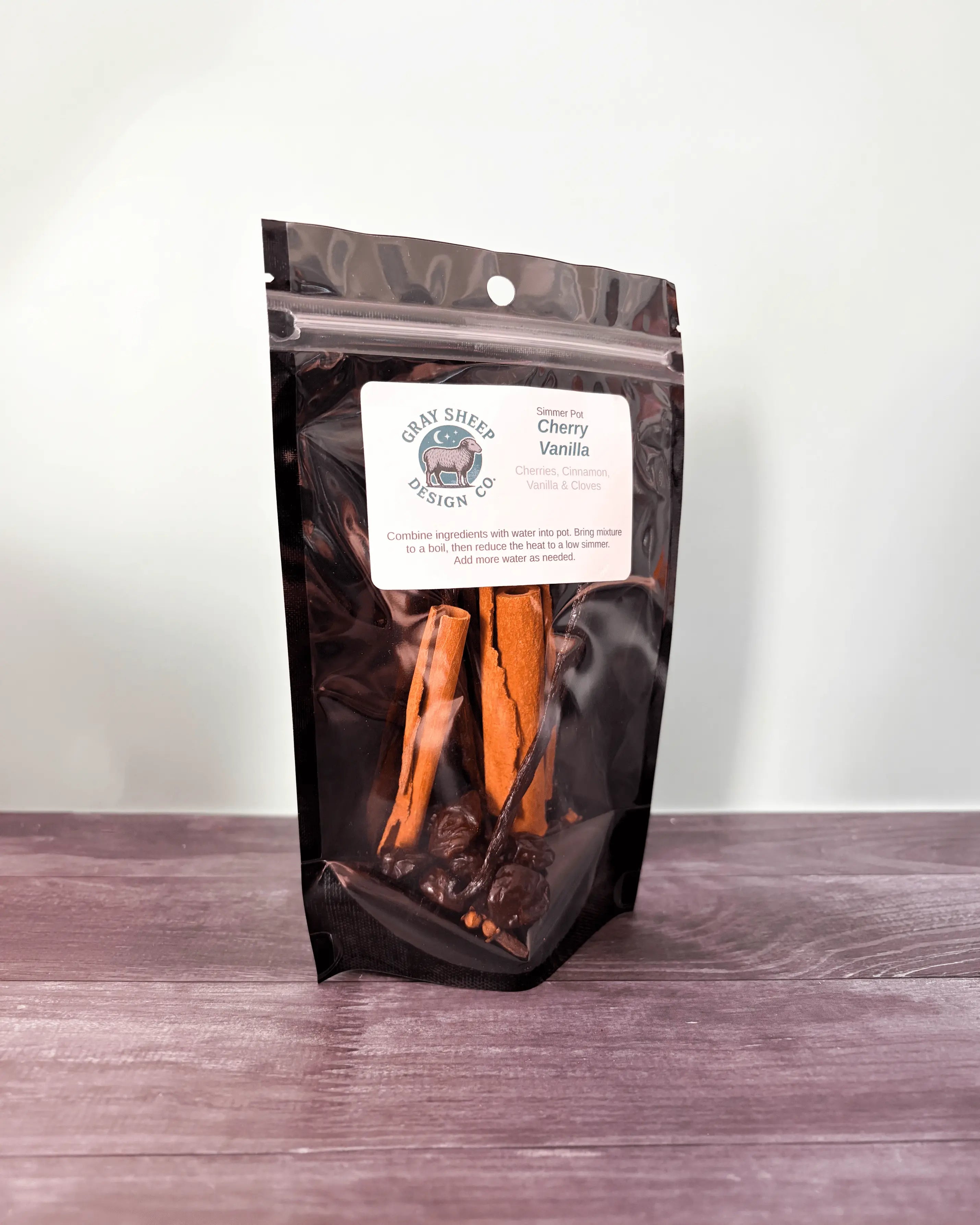 Cherry Vanilla simmer pot in a resealable black pouch, cinnamon sticks and vanilla beans visible through the window.