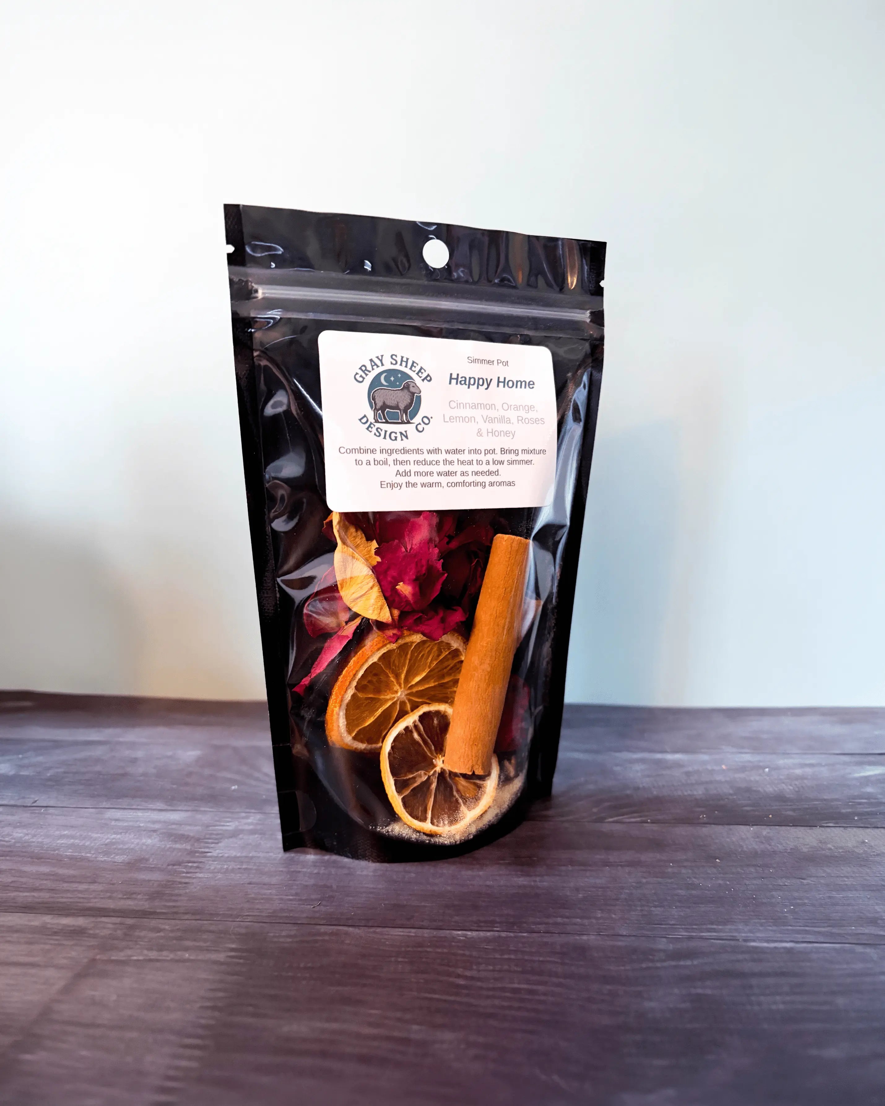 Happy Home simmer pot in a resealable black pouch, dried orange and cinnamon visible through the window.