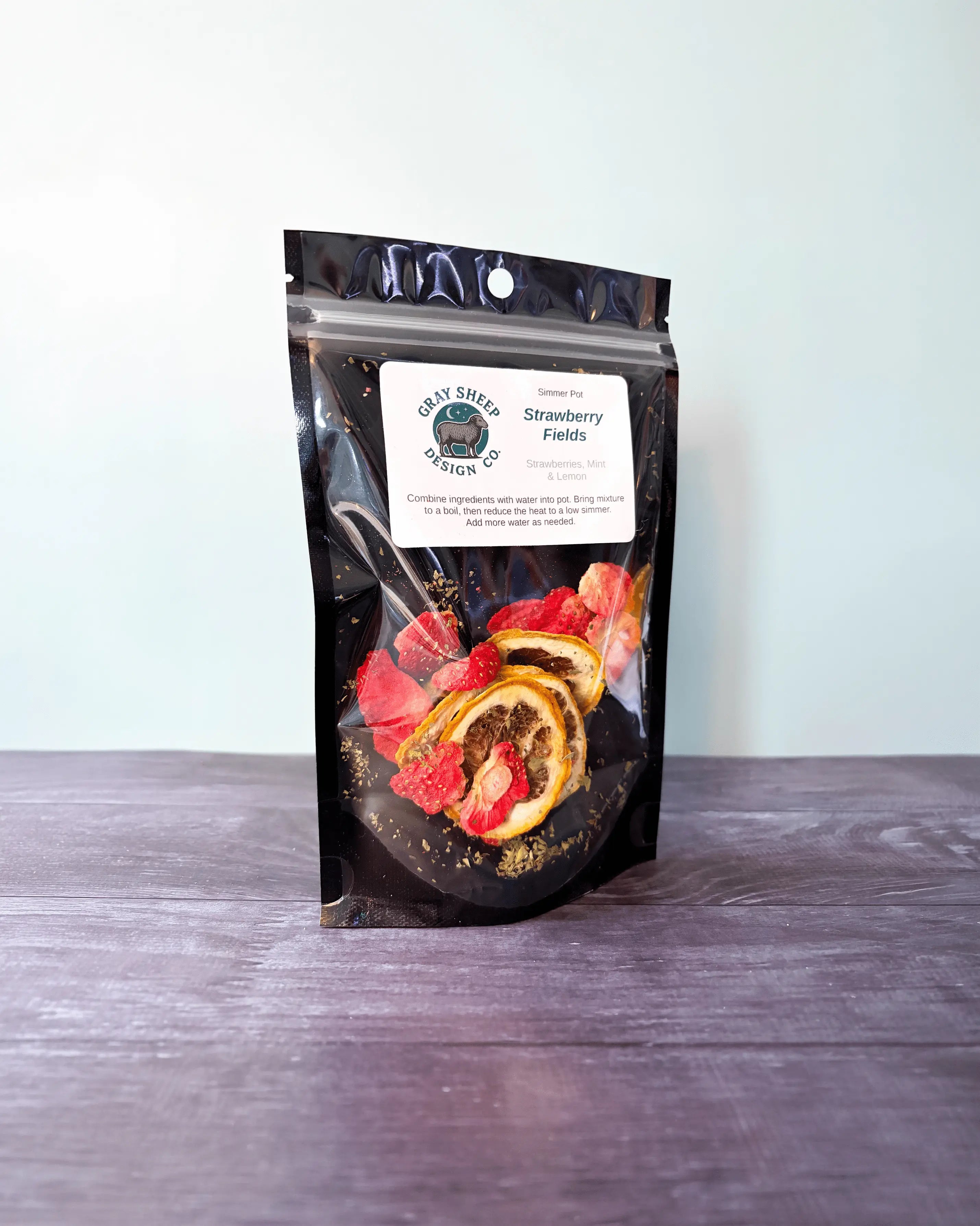Strawberry Fields simmer pot in a resealable black pouch, dried strawberries and lemon slices visible through the window.